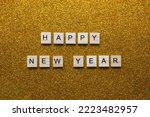 Happy new year written in english with scrabble letters on gold 