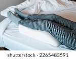 Small photo of a man in bed leans his legs on a leg elevation pillow made of memory foam