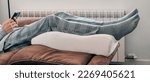 Small photo of a man leans his legs on a leg elevation pillow made of memory foam, resting on the sofa, in a panoramic format to use as web banner or header