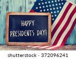 the text happy presidents day written in a chalkboard and a flag of the United States, on a rustic wooden background