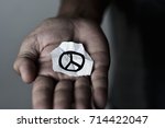 closeup of a young man with a piece of paper with a peace symbol drawn in it, in the palm of his hand