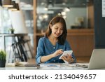 Small photo of Portrait of asian business woman paying bills online with laptop in office. Beautiful girl with computer and chequebook, happy paying bills. Startup business financial calculate account concept