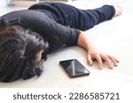Small photo of Woman fainted on the floor at home, phone fallen near her hand.