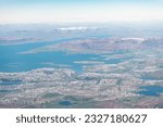 Iceland urban city bird's eye aerial high angle view of Reykjavik from airplane window above and snowcapped mountains