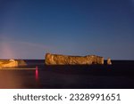 Famous Rocher Perce rock in Gaspe Peninsula, Quebec, Gaspesie region in Canada at dark night sky stars at Saint Lawrence gulf and red reflection