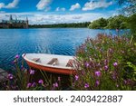 View of boat parked at lake shoreline on nice summer day; wildflowers in foreground 