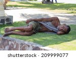 Small photo of DUMAGUETE, PHILIPPINES - FEBRUARY 18, 2014 : Poverty in Philippines, a unidentified beggar man sleeping on the street. Poverty and unemployment are high among uneducated people.