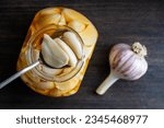 Small photo of Spoon with sliced garlic cloves in honey over the opened honey jar, top view, close up, copy space. Honey infused garlic