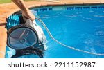 Small photo of Man pulling out the robotic pool cleaner with his hand. Pool robot for maintenance of the floor and walls automatically. Pool robot that sucks up dirt from the bottom