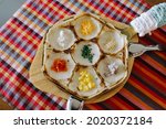 Small photo of Thai traditional dessert, local name is Khanom Khrok. It is Local Thai food, Kind of Thai sweetmeat, sweetmeat. kind, dessert. It cooks in special pan with small pit. A pan put on bamboo table.