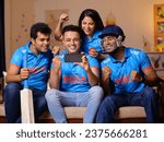 Small photo of A group of fans in Indian jerseys sitting on couch and watching live cricket match on phone - cricket fever, . Indian cricket fans are engrossed in checking the live score, placing online bets