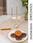 Small photo of Lighted Hanukkah with one candle and shamash on the first day of Hanukkah on the festive table next to donuts and a vase of flowers.