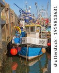 Small photo of Scarborough, UK. April 16, 2021. A fishing trawler is moored low down alongside a quay with other boats close astern. A clear sky is above.