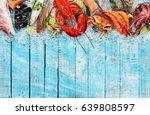 Whole lobster with seafood, crab, mussels, prawns, fish, salmon steak, mackerel and other shells served on crushed ice and wooden table