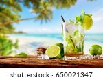 Fresh mojito drink placed on wooden planks, blur tropical beach on background. Summer drinks and beach vacation background