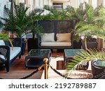 Tropical seating area with wicker sofas. Luxury seating area. Relaxation area with green palm trees and wicker chairs and tables