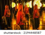 Small photo of Woman in a mirror maze. Mirror labyrinth. Fairy tale museum with mirrors. Blurred image