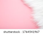Light, white fur on pastel pink table background. Empty place for text. 
