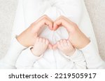 Heart shape created from young adult woman hands. Baby sitting on mother lap and holding mother fingers with hands. Closeup. Lovely emotional sentimental moment. Family concept. Point of view shot.