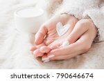 
Beautiful groomed woman's hands with cream jar on the fluffy blanket. Moisturizing cream for clean and soft skin in winter time. Heart shape created from cream. Love a body. Healthcare concept. 