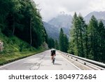 Professional road cyclist on fast and light carbon bicycle descends mountain road in Alps Dolomites. Fit and athletic man on recreational ride trip or training camp, enjoy time outdoors on bike