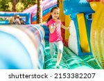 Small photo of Happy little girl having lots of fun on a jumping castle during sliding.