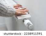 Small photo of The child's hands warm their hands near the heating radiator. Saving gas in the heating season.