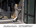 Woman locking smartlock on the entrance door using a smart phone. Concept of using smart electronic locks with keyless access