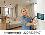 Small photo of Side view pleasant young woman using smart home system or activating modern alarm system before leaving apartment. Happy lady turning off easy security technology, when returning house or flat