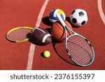 Small photo of A variety of sports equipment including an american football, a soccer ball, a tennis racket, a tennis ball, and a basketball