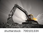 Excavator parked on stone ground against dramatic sky