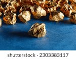 A group of pure shiny gold pieces on the rough background. Expensive noble metal. Golden nuggets. Gold ore. Symbol of wealth. Precious treasure. Concept of investing capital, finance, banking purpose.