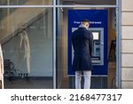 Small photo of Man using cash machine to withdraw money on high street