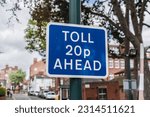 Small photo of Rectangle blue toll 20p ahead sign with trees in background, concept illustration.