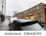 Small photo of Birmingham, England, November 4th 2023. A wet vehicle's rooftop in the foreground, with a Hertz car rental brick storefront in the background.