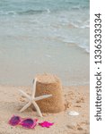 Small photo of Summer holidays concept. Vertical banner mockup. Pink sunglasses, sea star and a sand castle on the sand of a beach seaside. Happy weekend
