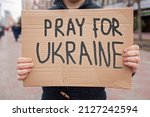 Middle aged civil man stands on crowded city street and holds a poster with anti-war message. Protest against the Russian intervention to Ukraine, activism and human rights movement