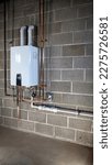 Small photo of Installation of a tankless water heater. A professional installation a tankless water heater. A licensed plumber installed a new tankless water heater on a block basement wall.