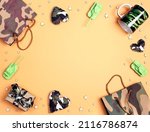 Small photo of Frame of camouflage hearts, gifts, bag, mug and origami paper tanks on yellow background. Top down composition with cope space. Defender of the Fatherland Day, February 23.