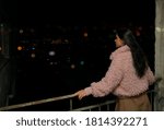 stylish asian woman  relaxing on rooftop. night  city. blurred town on background.
