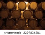 Small photo of oak wooden Wine barrels in a old, dark wine cellar. front view. Cognac store basement of wooden brandy, beer. Wine storage vault. row of stacks of whisky barrels, set down to mature, in warehouse.
