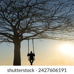 Small photo of Back view of man swinging on the wooden swing on big leafless tree. Scenic landscape. rear view of middle age unrecognisable man swinging on swing with rope under mountains.
