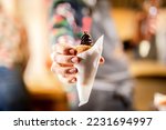 Holding a traditional hungarian stuffed chimney cake dessert in hand with bokeh background