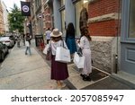 Small photo of New York NY USA_October 9, 2021 Customers with their The RealReal luxury consignment shopping bags wait in line to enter another second-hand luxury clothing retailer, What Goes Around Comes Around
