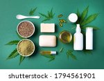 Flat lay with hemp extract products - cosmetics, lotion, face cream, body butter, soap bars, cannabis leaves, seeds, hemp oi, capsules, protein powder, flour on green background. Top view. Copy space.