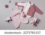 Small photo of Set of pink clothes and accessories fot newborn girl. Toys, bodysuit, romper, knitted cardigan, shoes, bib on grey background. Mock up tor text. Baby shower concept. Flat lay, top view.
