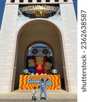 Small photo of A young mother and her daughter pose expressively in front of the Minion Land ride at Universal Studios Singapore. With the background of the Minions statue: Sentosa, Singapore - 17 July 2023.