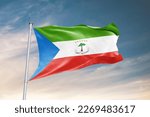 Waving flag of Equatorial Guinea in beautiful sky. Equatorial Guinea flag for independence day. The symbol of the state on wavy fabric.