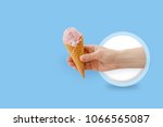 Ice cream cone in hand on blue background.