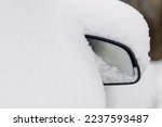 Travel in winter. Snowy car. Winter season cleaning. Heavy snow. Snow covered car mirror.
